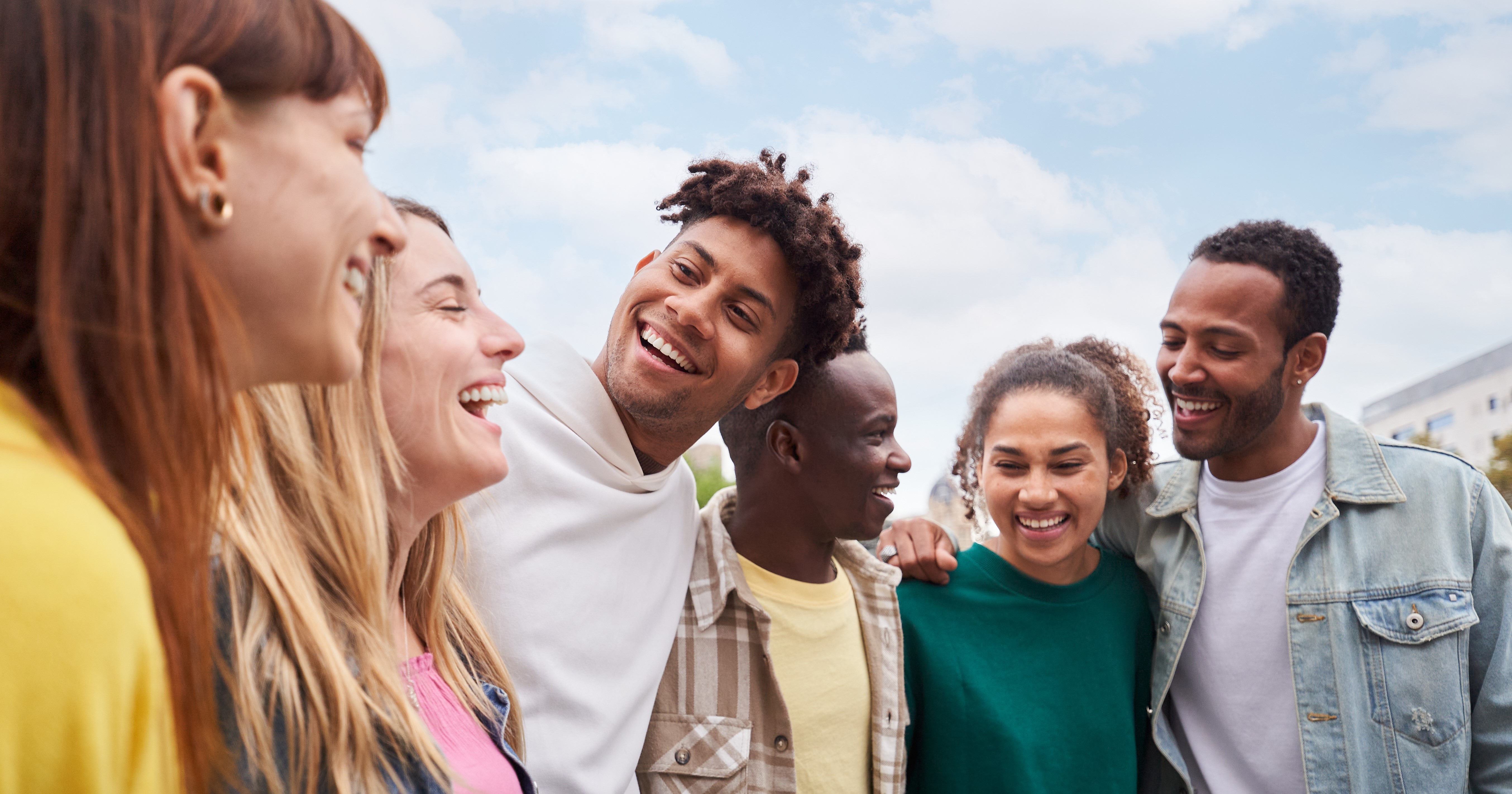 Grupo de jovens que representam diversidade se abraçando.