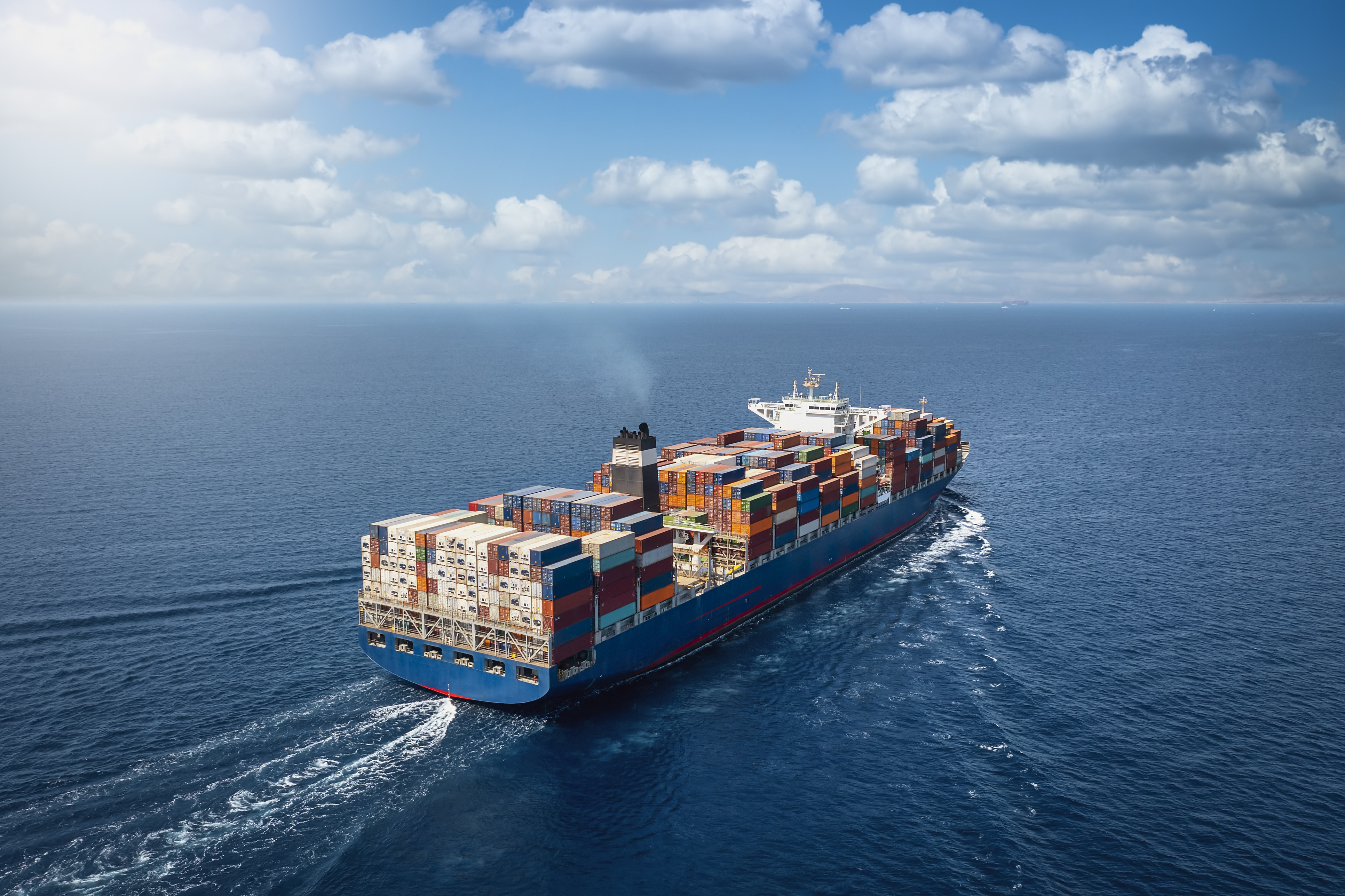 Navio cargueiro em alto-mar transportando contêineres, simbolizando os processos de carga e descarga no transporte marítimo internacional.
